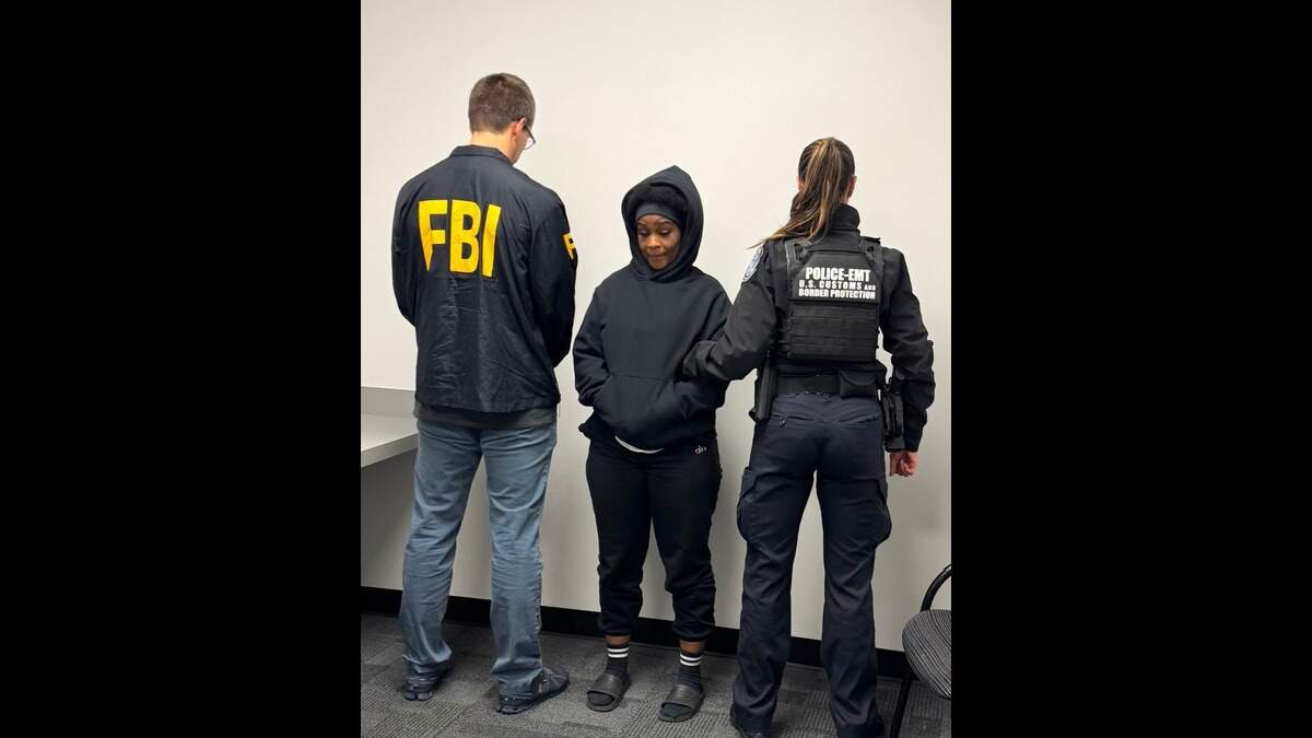 Elaine Escoe flanked by FBI agents as she’s brought back from Jamaica.